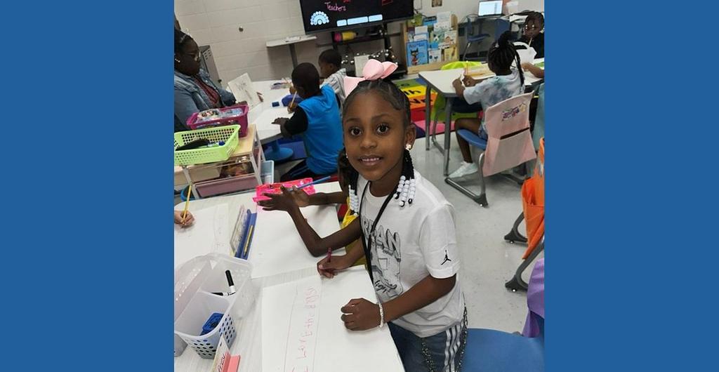 Student smiling as she works at her desk