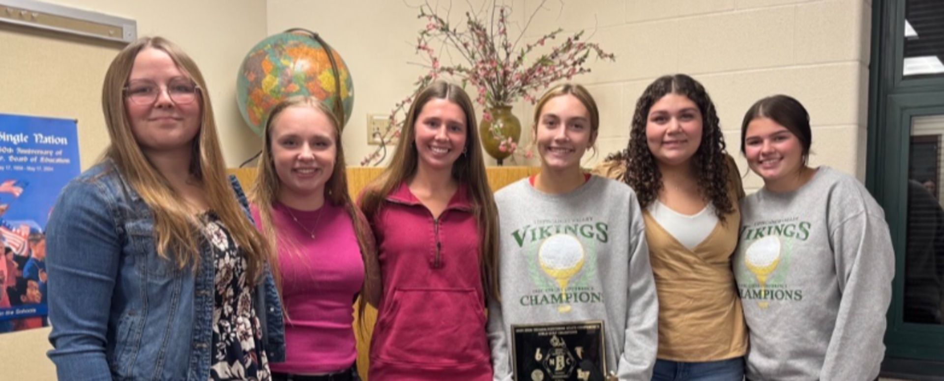 Group of six individuals posing together, holding a trophy.