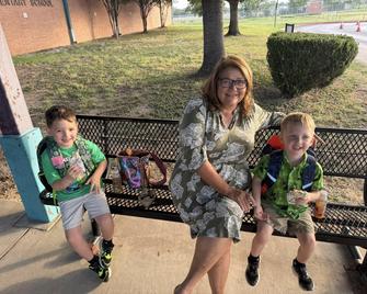 Grandmother in green dress sitting on bench between grandsons holding tacos