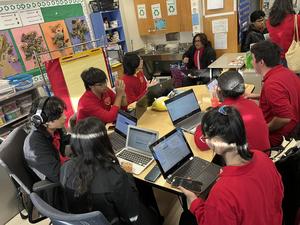 students in red focusing on the devices in front of them