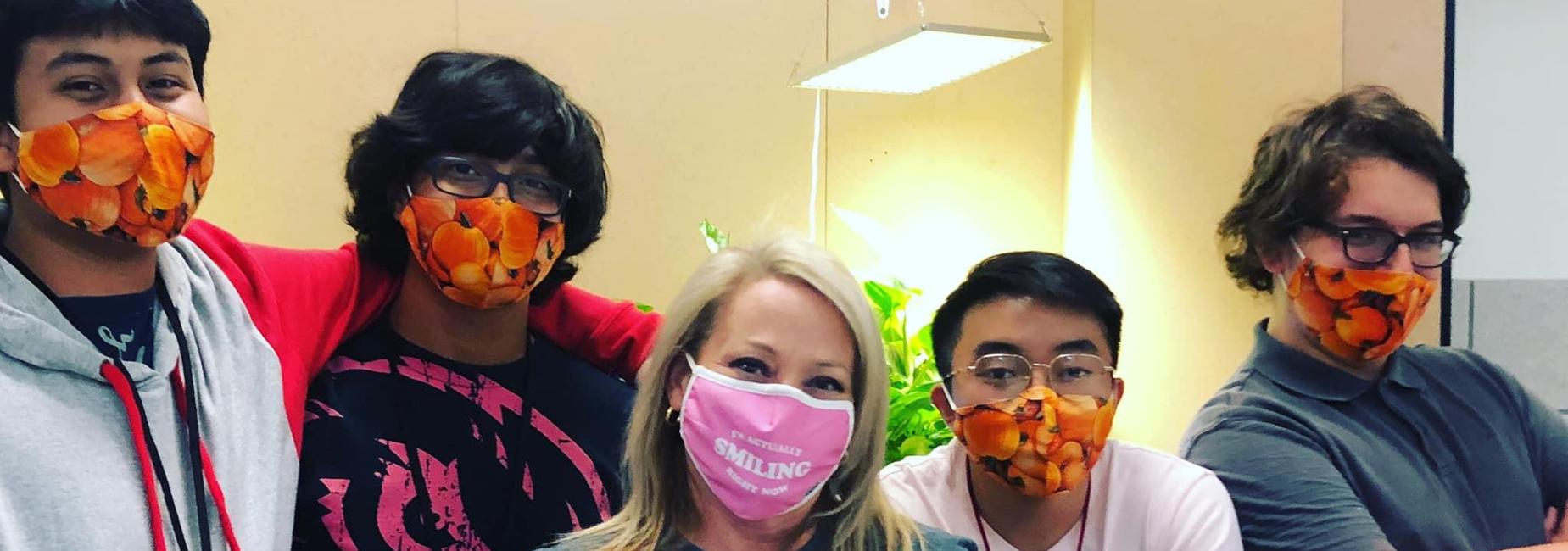students and counselor wearing pumpkin face masks