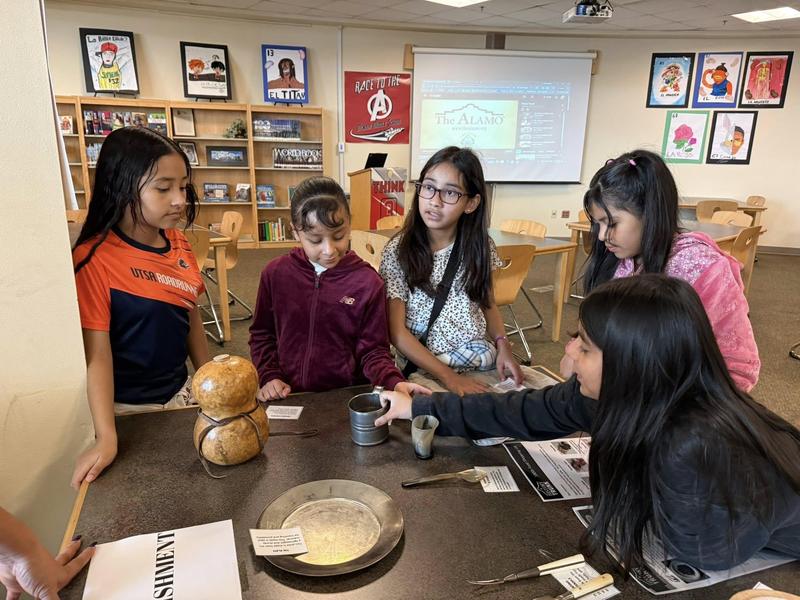 four girls looking at historical artifacts on a table
