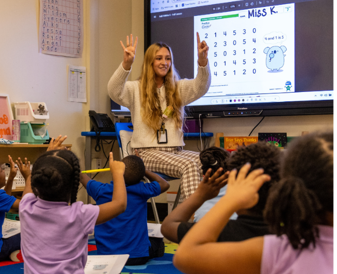 teacher in clasroom teaching students while they sit around her