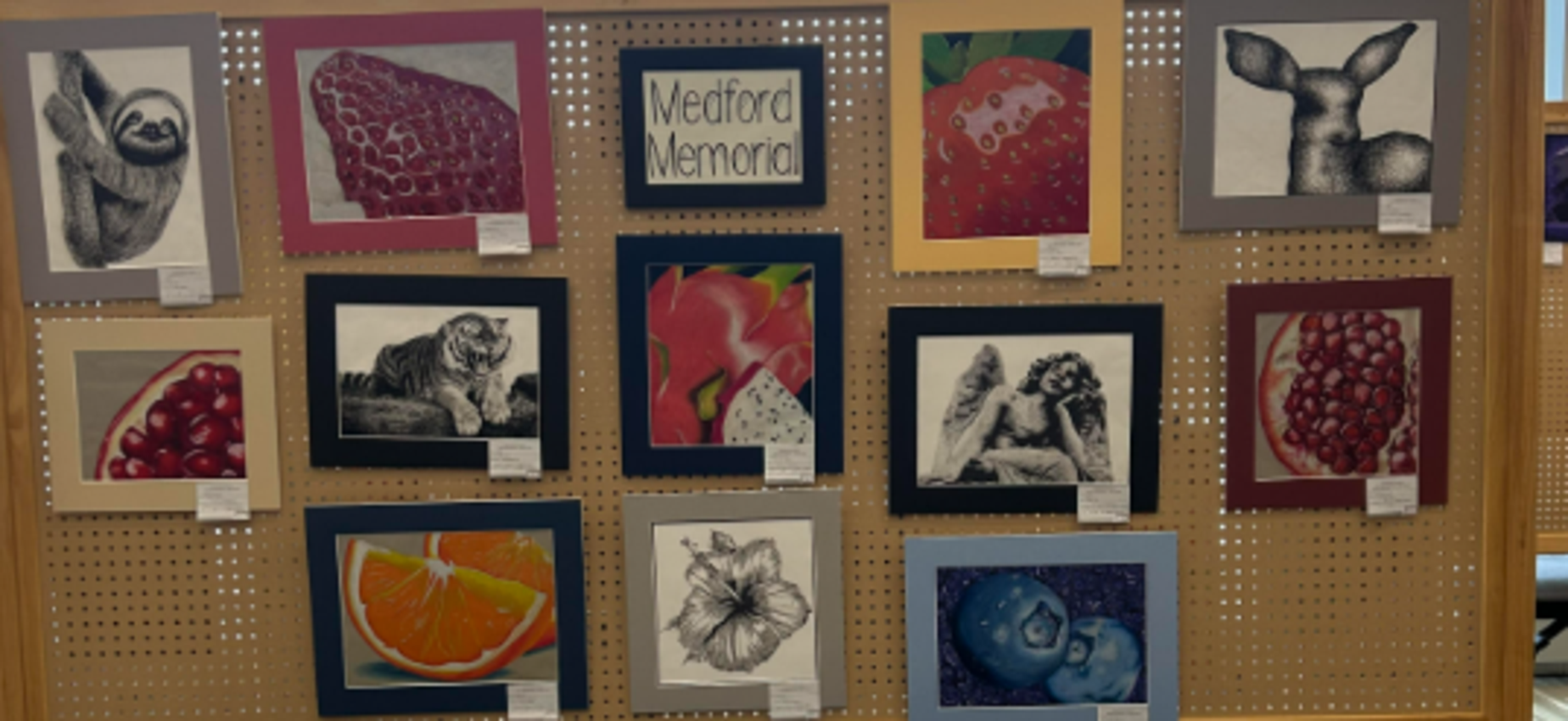 Art display featuring various drawings and paintings on a bulletin board.