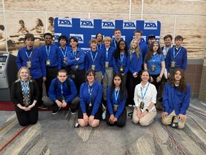 Students in blue shirts posing for team photo