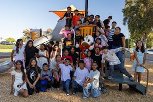 Wild Wing surrounded by a large group of students by the slide.