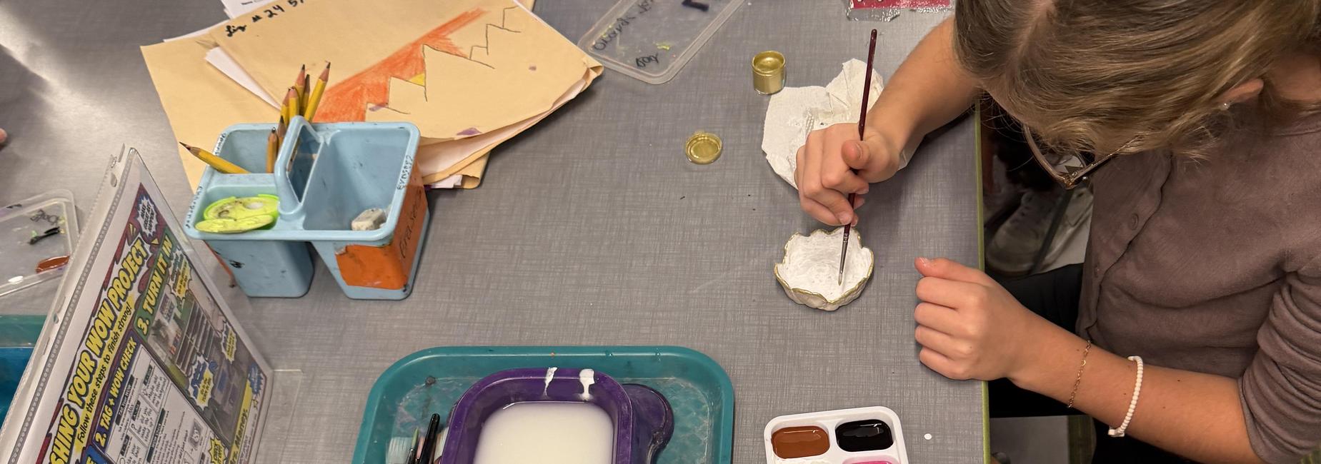 Art supplies on a table, including paint, brushes, and a palette.