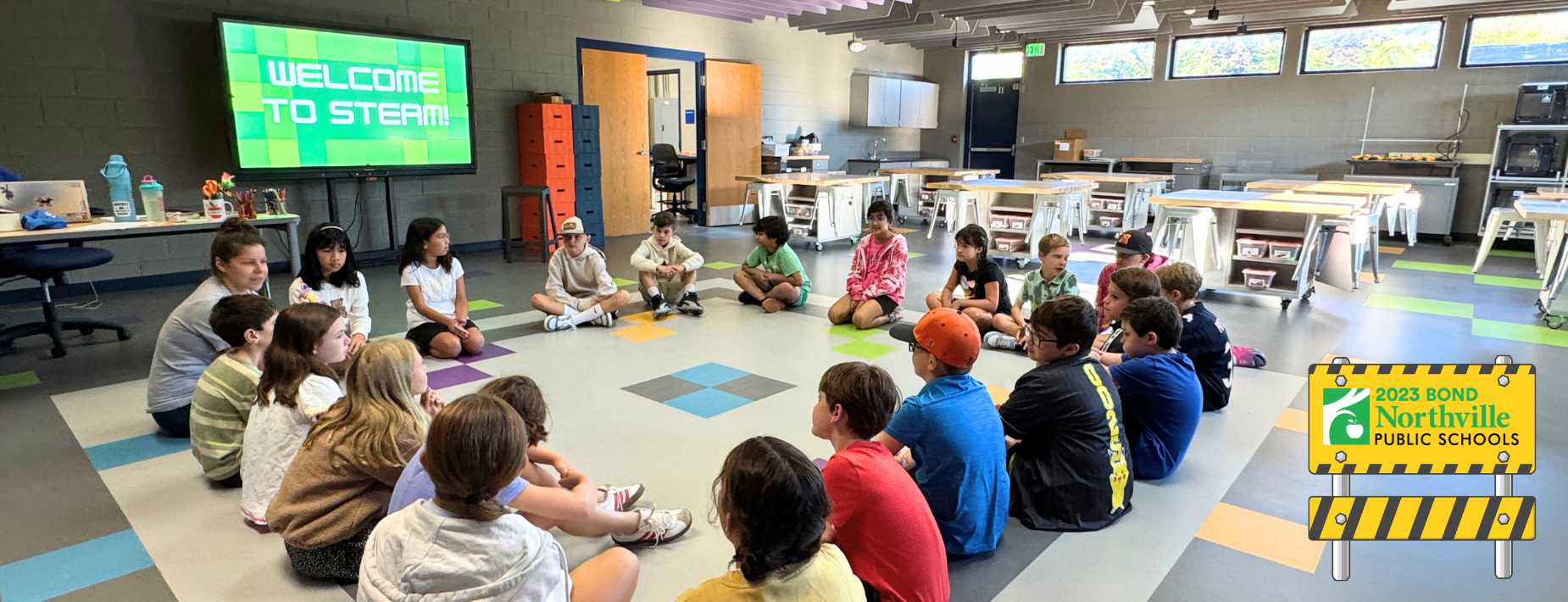 Students sitting on the ground in a circle in the Amerman STEAM space.