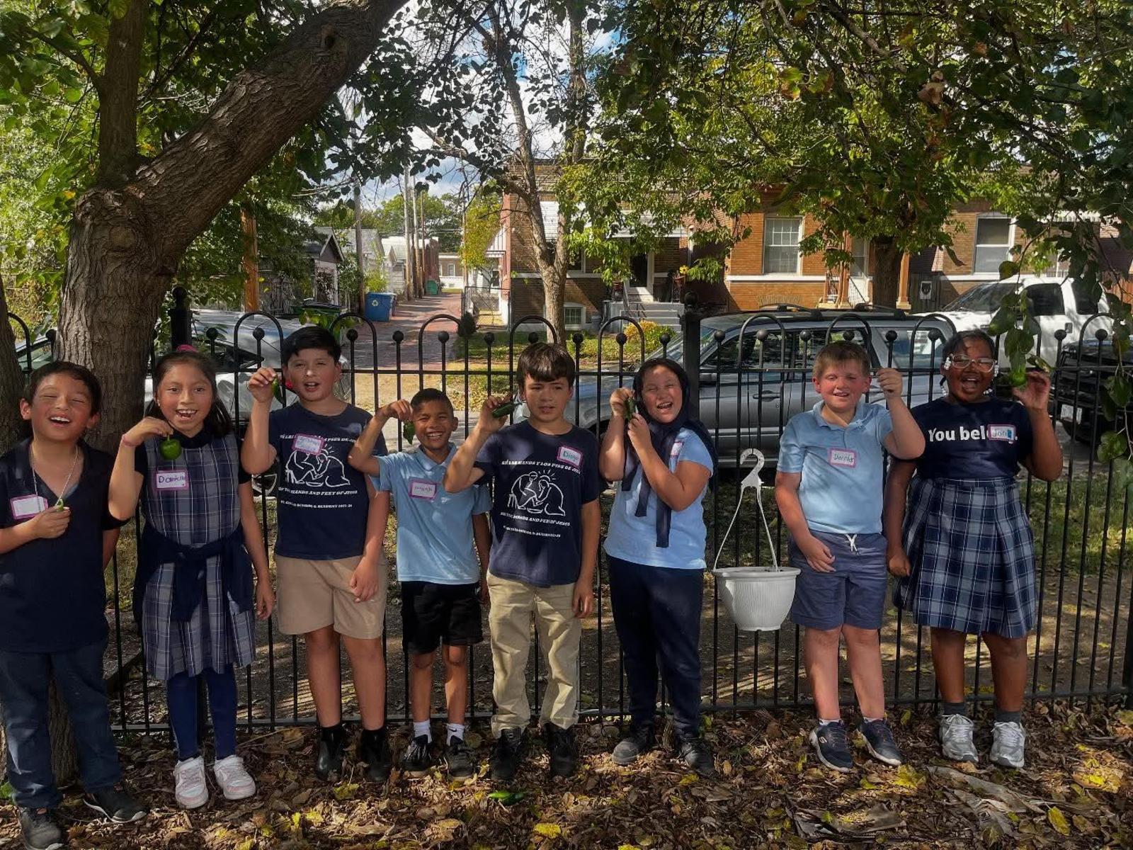 a picture of students in a garden showing the items they've grown.