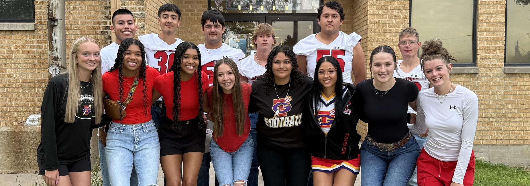 A diverse group of high school students posing together in team jerseys and casual clothing.