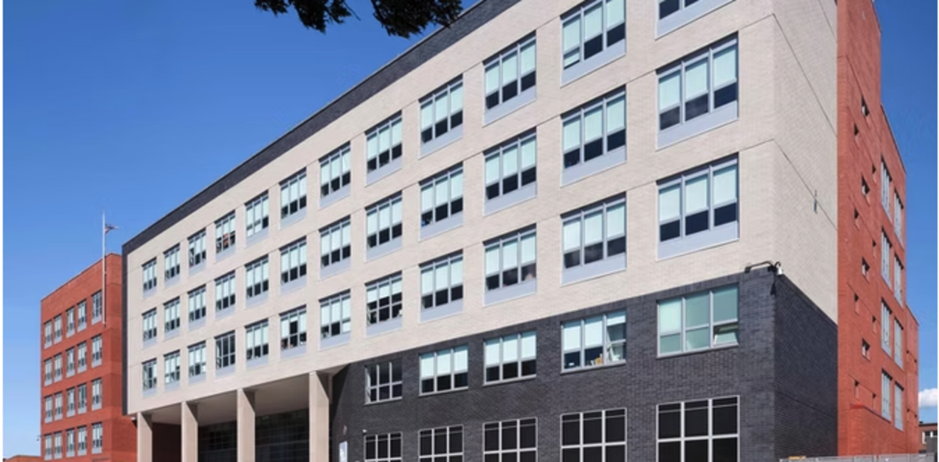 Modern school building with many windows against a clear blue sky.