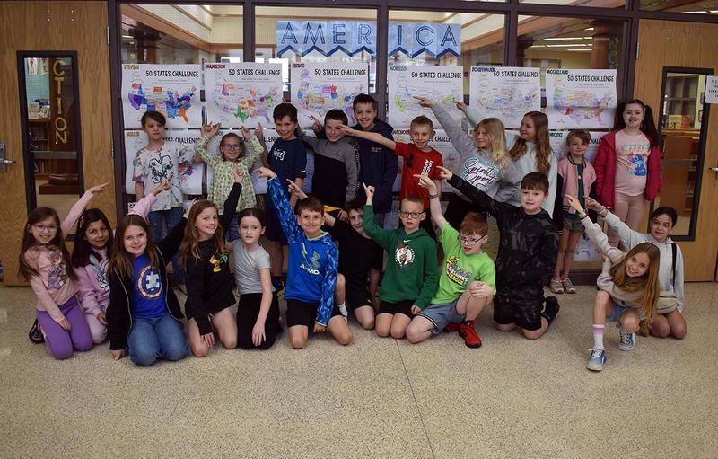 Students celebrating in front of '50 States Challenge' displays with colorful maps.