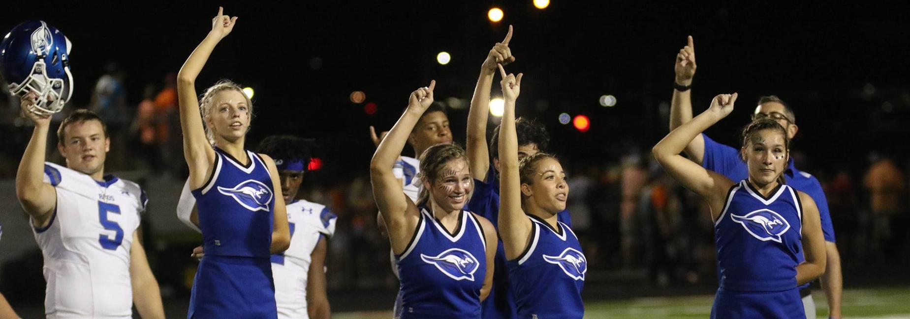 Cheerleaders and football players singing the school song