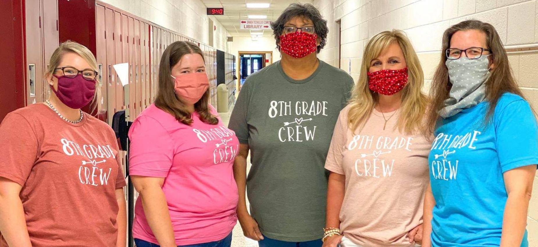 Five teachers wear masks in a hallway.