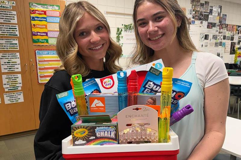 Two students hold an Easter basket filled with toys