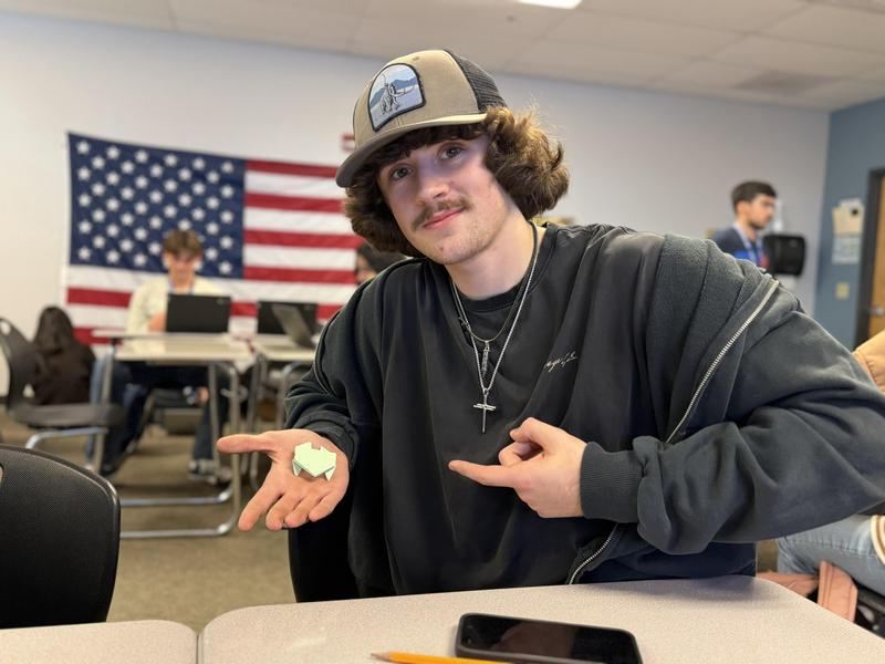 student holding paper frog