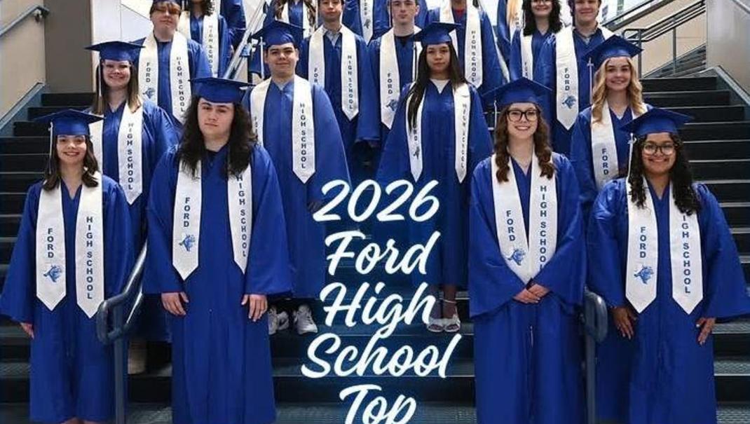 Graduating seniors in blue gowns and caps posing on a staircase.