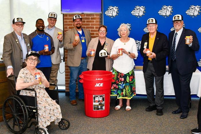 A group of people and smiling, holding peanut butter jars