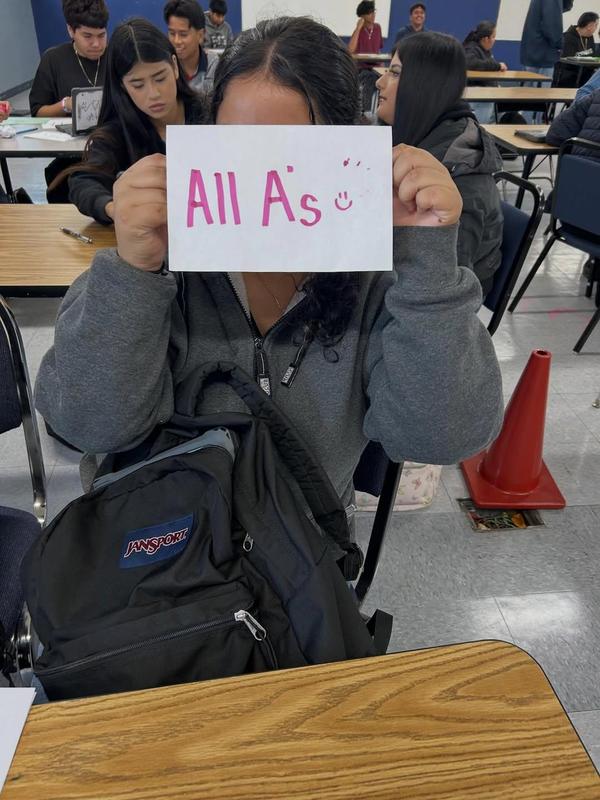 student holds up an all A's paper