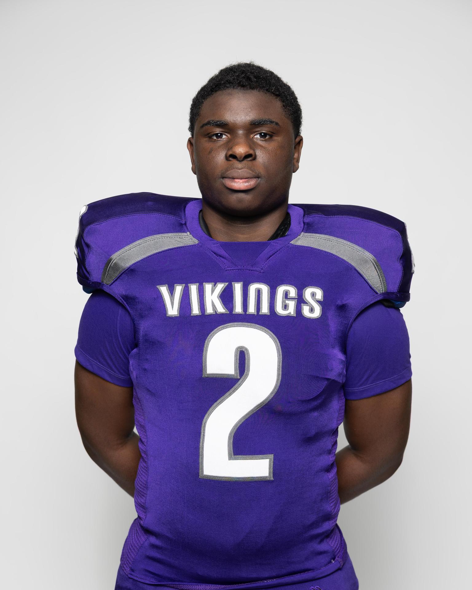 Athlete in a purple football uniform with the number 2, standing confidently.