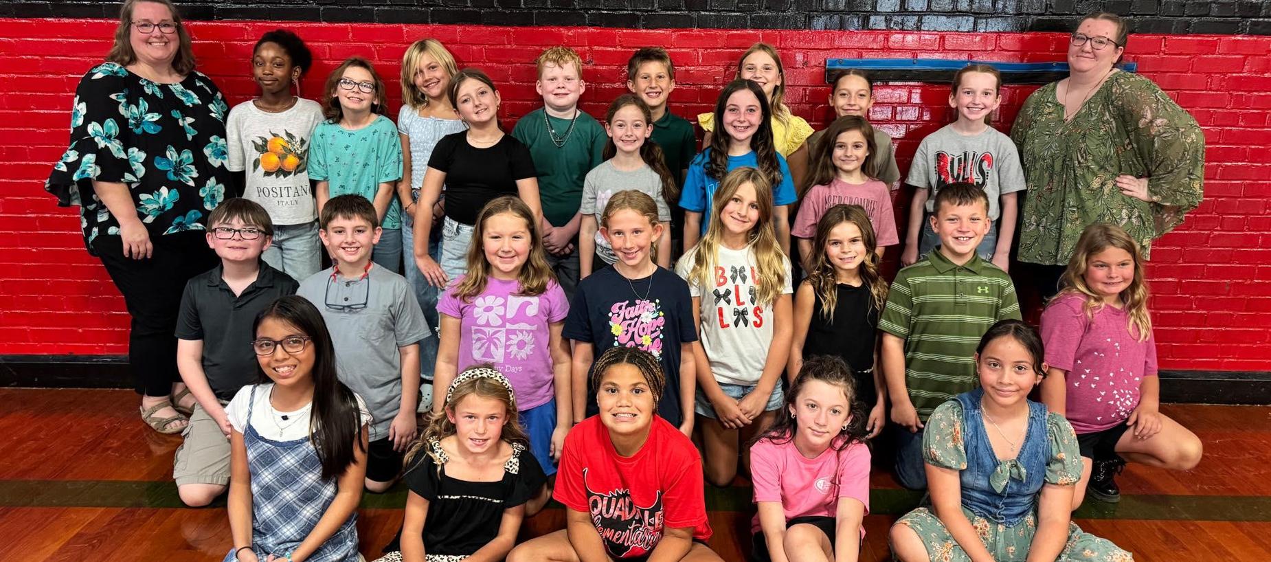 Group of students and two teachers in the gym