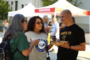 Two female and one male Whittier Union staff members stand in a half circle together with coffee and pastries in hand reconnecting during Staff Day One on August 10.