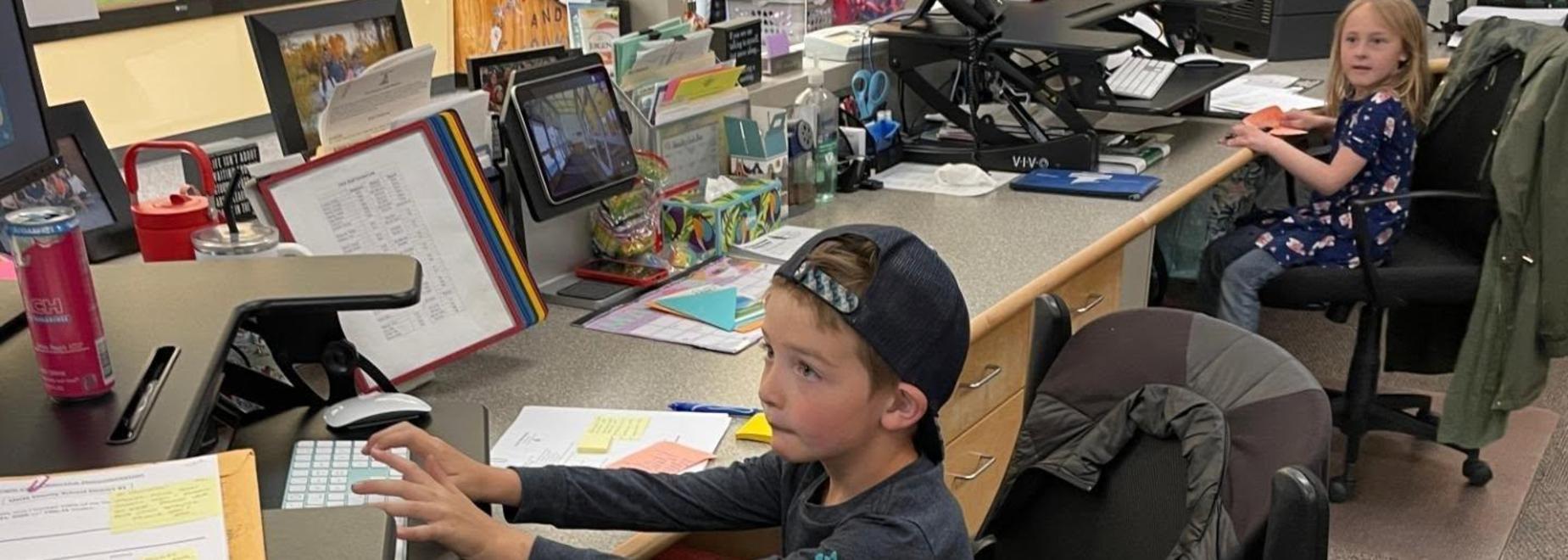 Young boy sitting at a desk, typing on a computer.