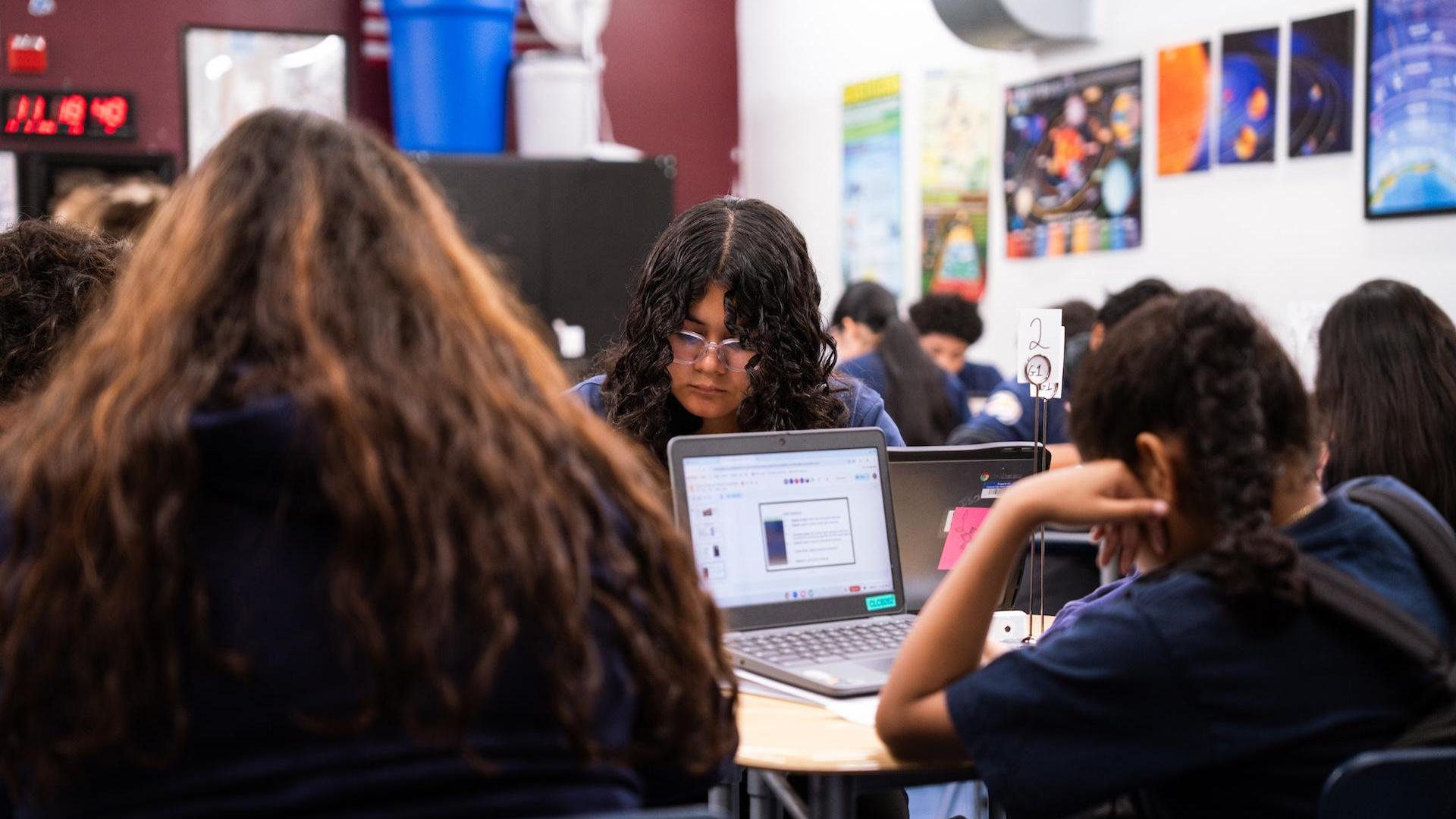 Students focused on laptops in a classroom setting.
