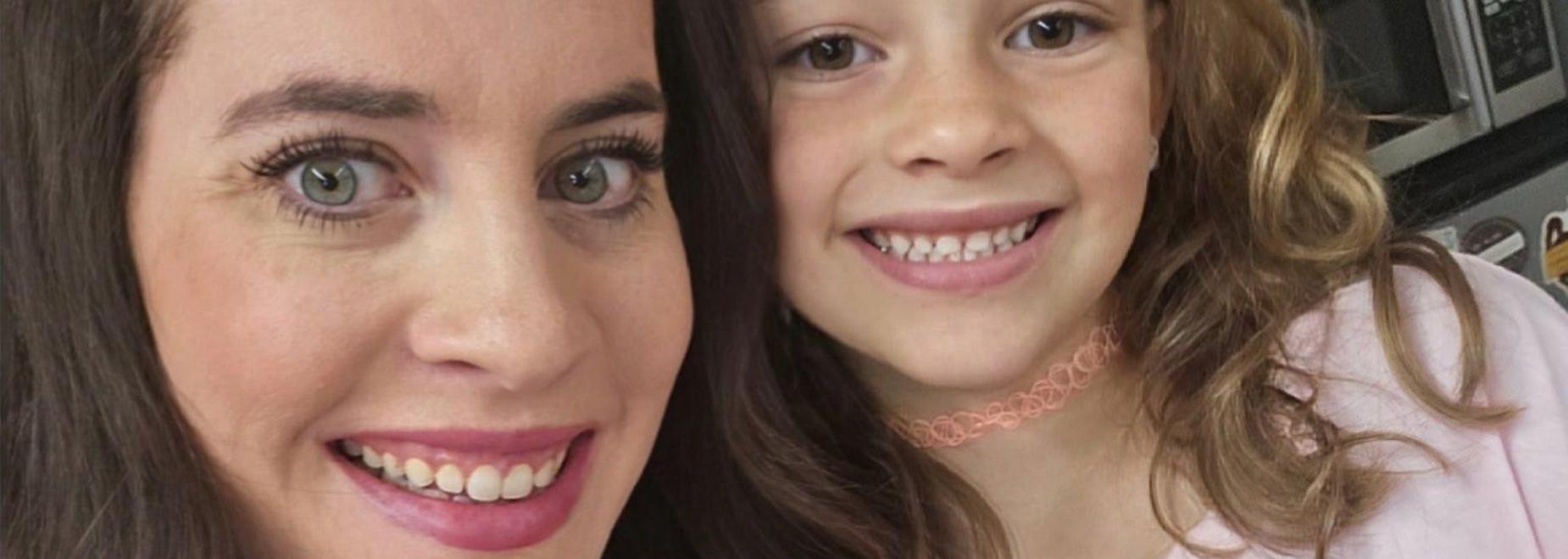 Two smiling individuals wearing matching pink shirts with text.