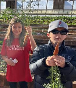James River Day School 4th graders showing off carrots they harvested.