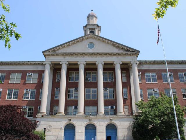 Historic school building with tall columns and flag in front.