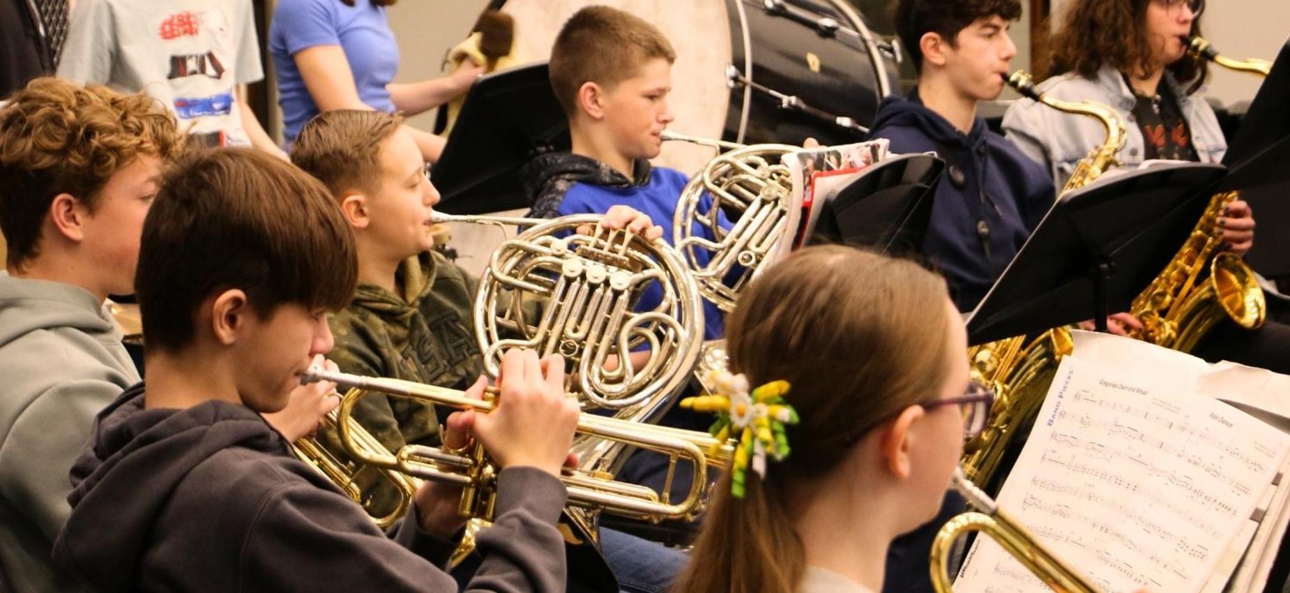 A group of students play various brass instruments during a music rehearsal.