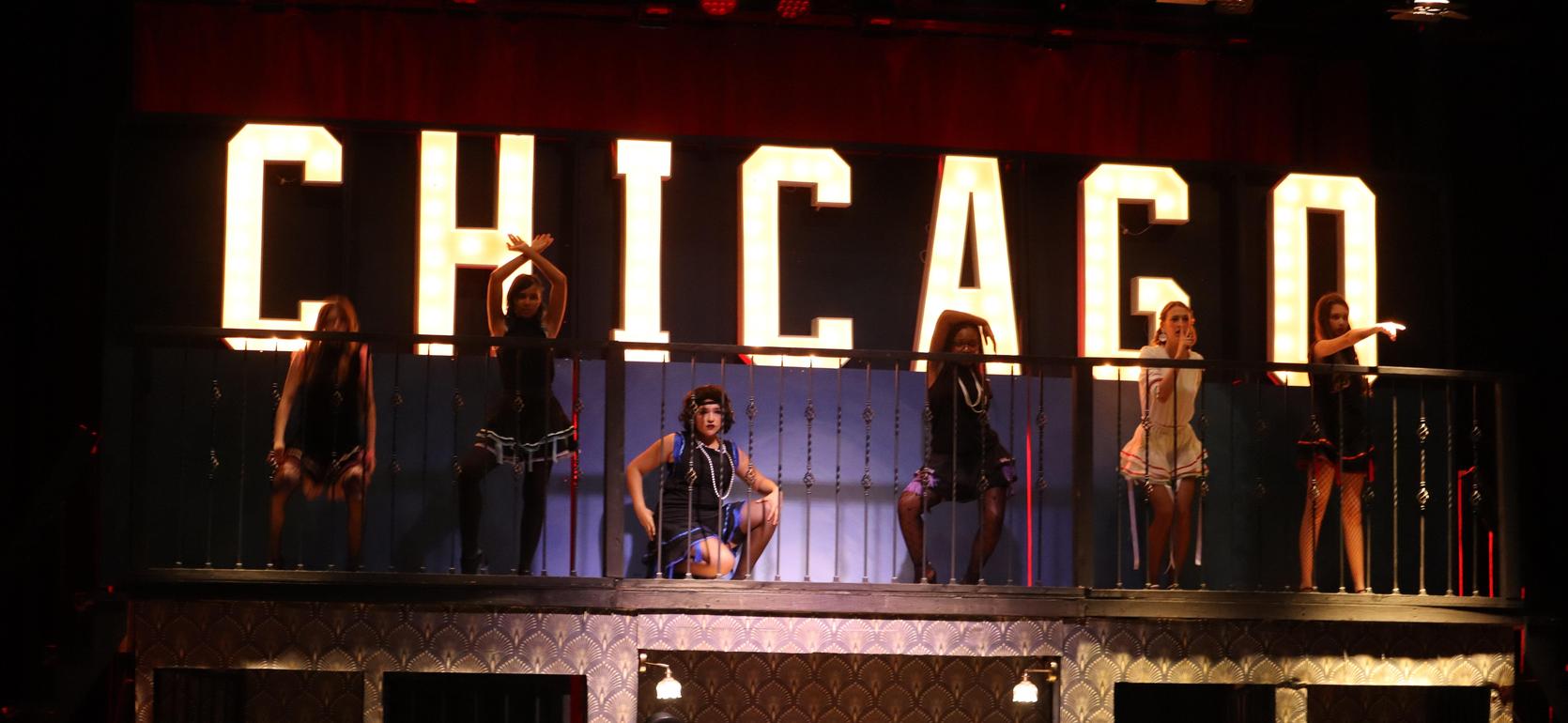 Performers on stage in front of a large 'CHICAGO' sign.