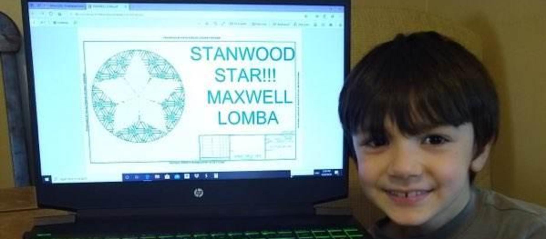 boy sitting beside his computer showing he got a star from his school