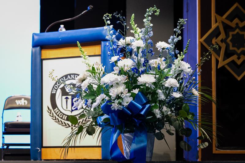 A wreath is set in front of a podium with the Woodland Hills logo