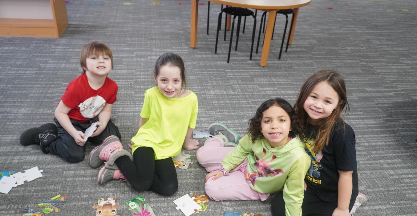 Four students work on a large puzzle in the library.