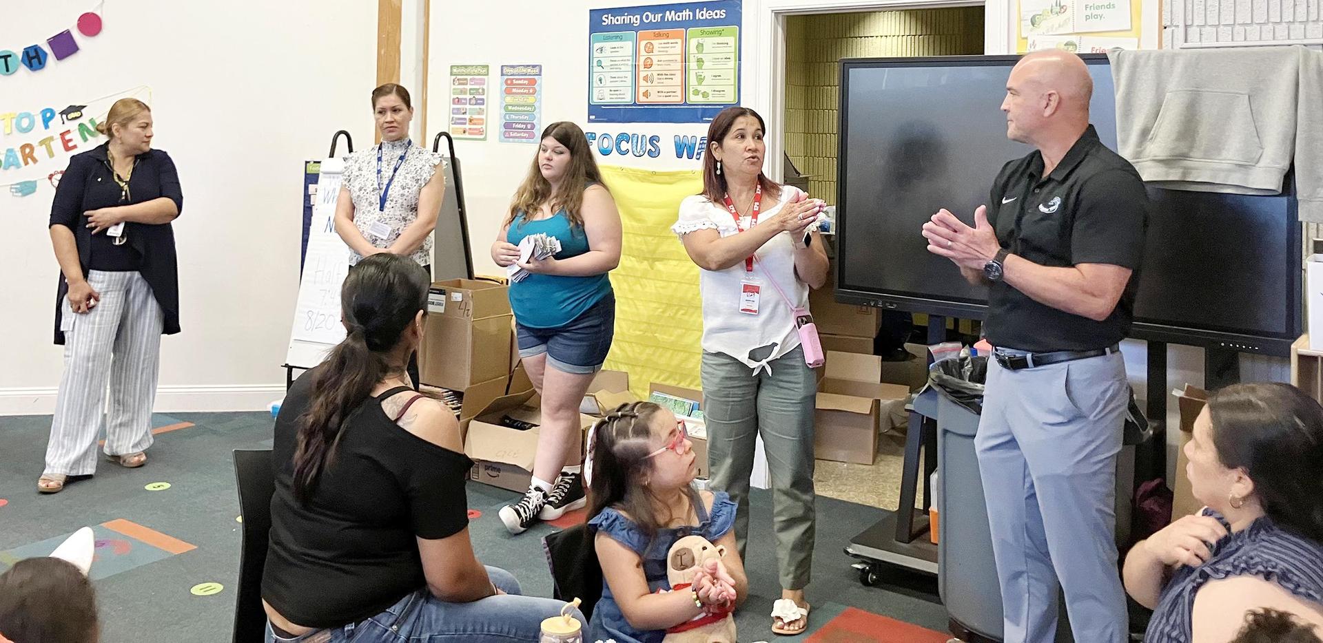 Adults at the head of a classroom, talking to parents