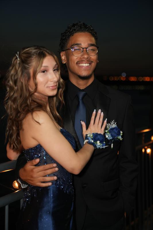 A couple poses together, smiling against a nighttime backdrop.