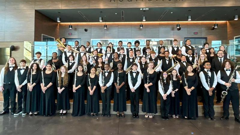 Group photo of band in uniform in front of a trophy case