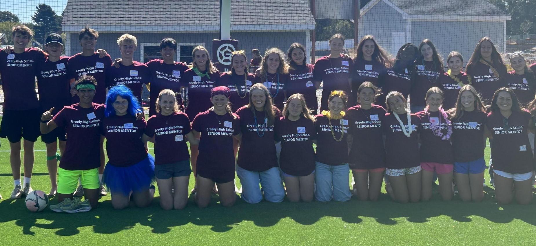 Group of high school students in matching shirts posing together on a field.