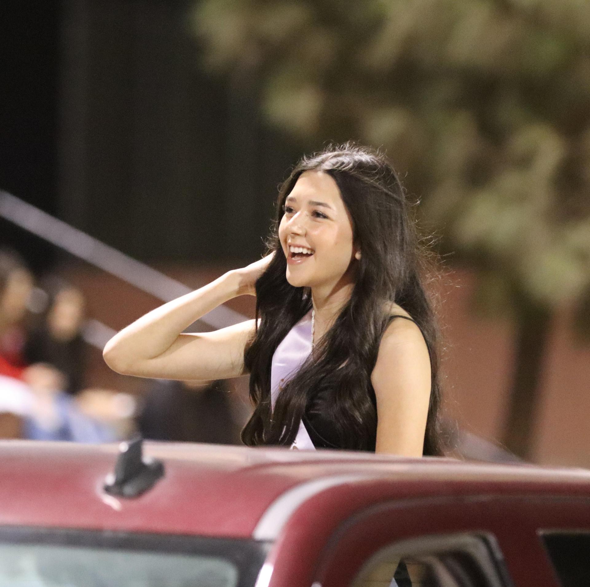 homecoming king and queen candidates entering the stadium in trucks