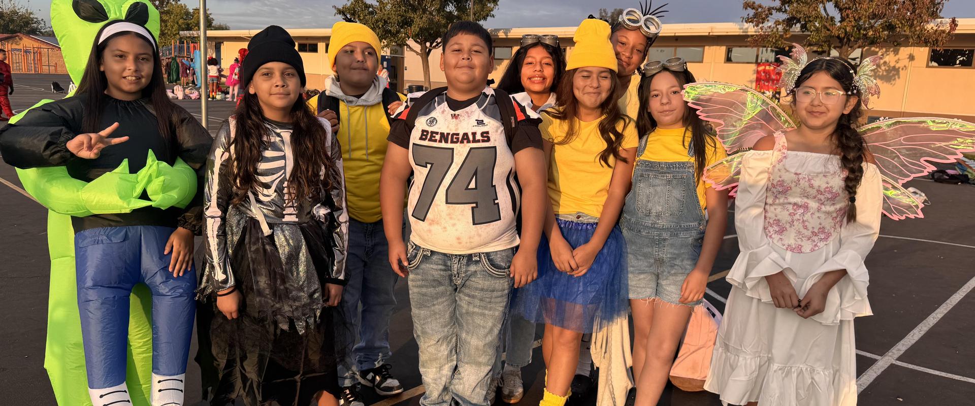 Group of children in various costumes smiling together outdoors.