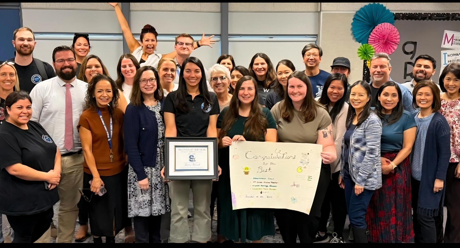 Group photo of a celebration with people holding a certificate and a poster.