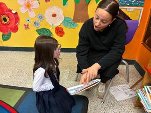 a seventh grade girl read her Gadol picture book to a kindergarten student.