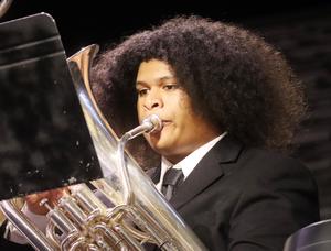 Male student plays french horn in concert setting