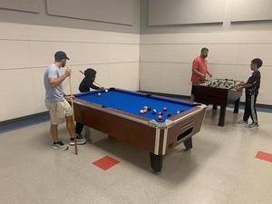 A mentor plays pool with his mentee