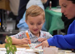 a young boy playing bingo with his mother pointing to the bingo card