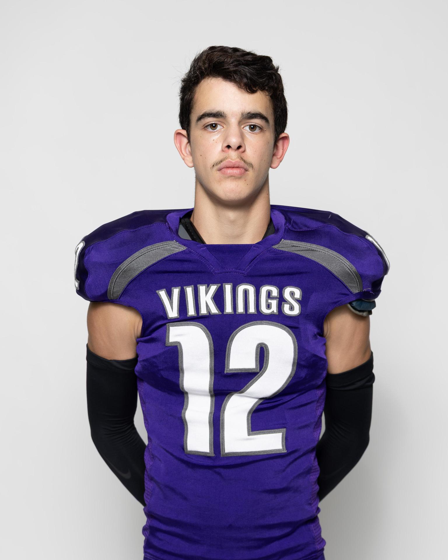 Young athlete in a purple football jersey with the number 12, standing confidently.
