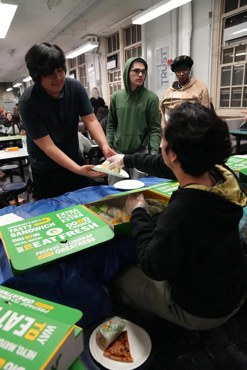 A group of people interacting at a table with food items during an event.