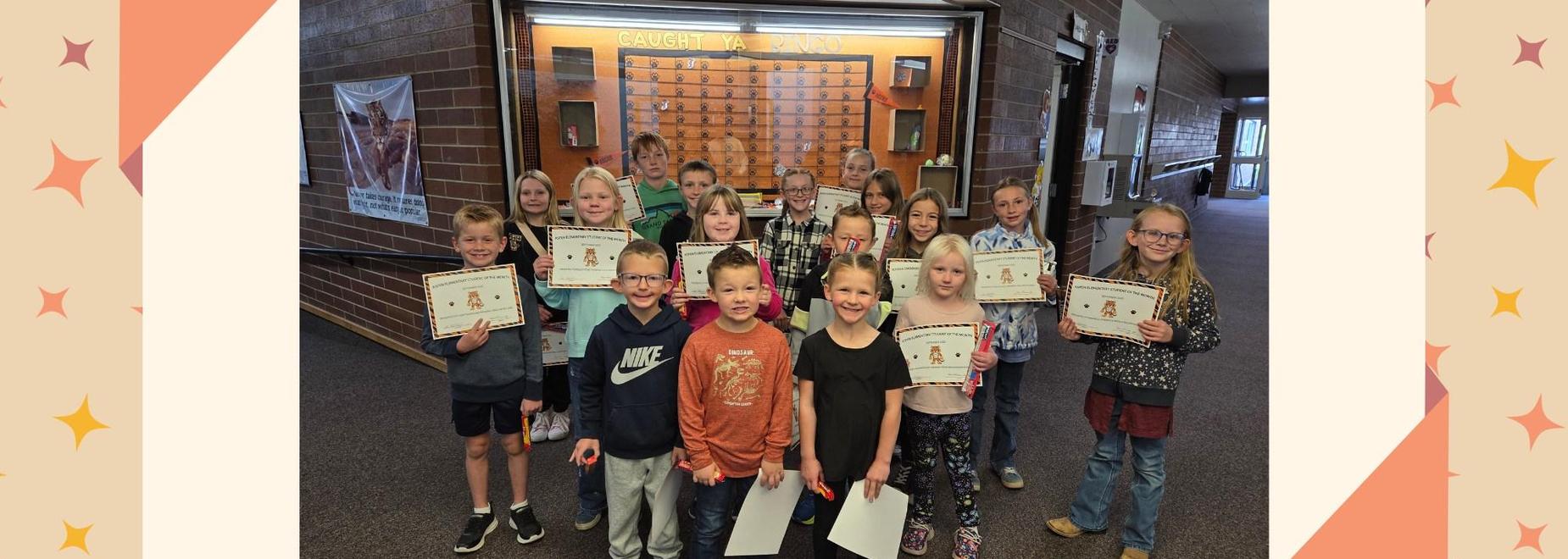 Group of children holding certificates celebrating achievements in a school hallway.